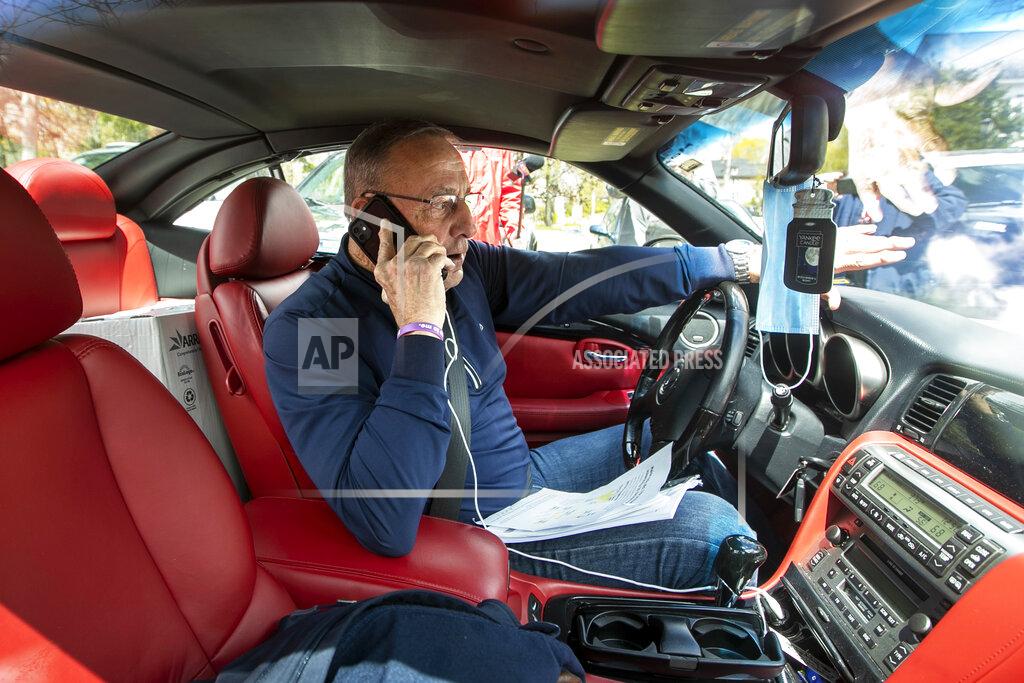 Robert F. Bukaty Former Gov. Paul LePage, sitting in a Lexus SC 430, uses his cell phone to address protesters rallying against the executive orders by Gov. Janet Mills to keep some Maine businesses closed to help prevent the spread of coronavirus, Saturday, May 16, 2020, in Augusta, Maine. His call was broadcast over speakers set up at the nearby rally. LePage, now a resident of Florida, stayed in his car parked near the rally. A speaker at the event said the former governor was quarantining. (AP Photo/Robert F. Bukaty)
