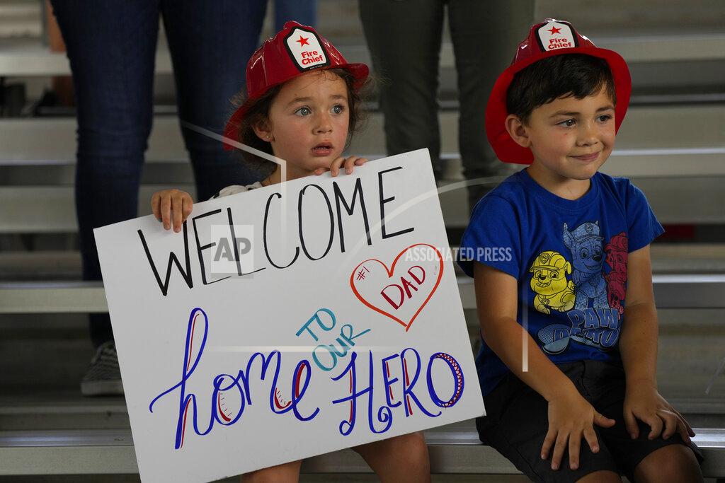 Rebecca Blackwell Isabella, 3, and Eric, 4, wait to welcome home their father, Capt. Eric Hernandez, as members of Miami-Dade Fire Rescue's urban search and rescue team are reunited with their families after weeks of working on the rubble pile at the collapsed Champlain Towers South condominium, on Friday, July 23, 2021, in Doral, Fla. (AP Photo/Rebecca Blackwell)