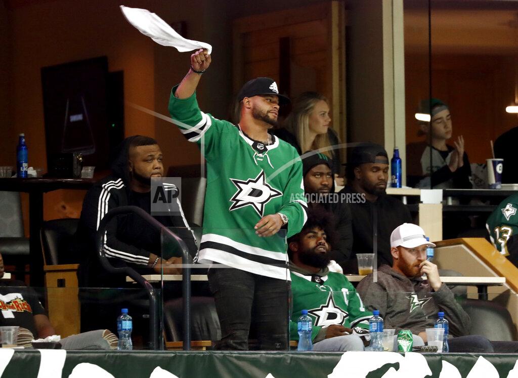 Tony Gutierrez Dallas Cowboys quarterback Das Prescott stands and waves his rally towels as he and running back Zeke Elliott, sitting right, watch in the third period of Game 6 in an NHL hockey first-round playoff series between the Dallas Stars and the Nashville Predators in Dallas, Monday, April 22, 2019. (AP Photo/Tony Gutierrez)