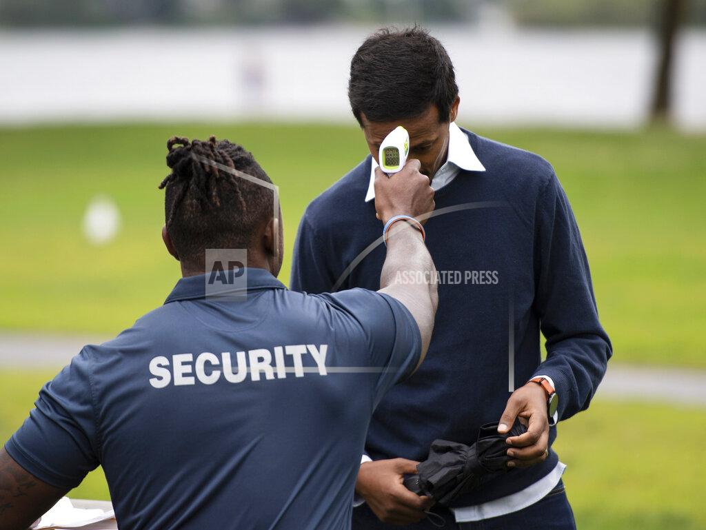 Justin Tang A security guard takes an attendee's temperature as a precaution against COVID-19 as they arrive at an event at Mooney's Bay Park in Ottawa, Ontario, on the Labour Day holiday weekend, Monday, Sept. 7, 2020. (Justin Tang/The Canadian Press via AP)