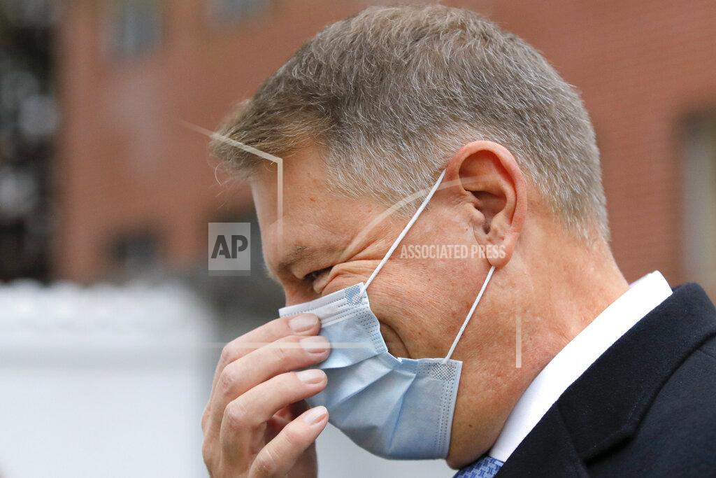 Vadim Ghirda Romanian President Klaus Iohannis adjusts his mask for protection against the COVID-19 infection after casting his vote in Bucharest, Romania, Sunday, Dec. 6, 2020. Voting started in Romania's legislative election expected to restore some measure of stability after five years of political and social turbulence with more than 18 million Romanians registered to vote for a new legislative body. (AP Photo/Vadim Ghirda)