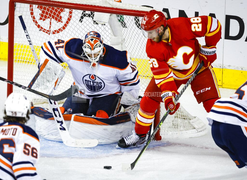 Jeff Mcintosh Edmonton Oilers goalie Mike Smith, left, blocks a shot from Calgary Flames forward Elias Lindholm during the second period of Game 2 of an NHL hockey Stanley Cup playoffs second-round series Friday, May 20, 2022, in Calgary, Alberta. (Jeff McIntosh/The Canadian Press via AP)