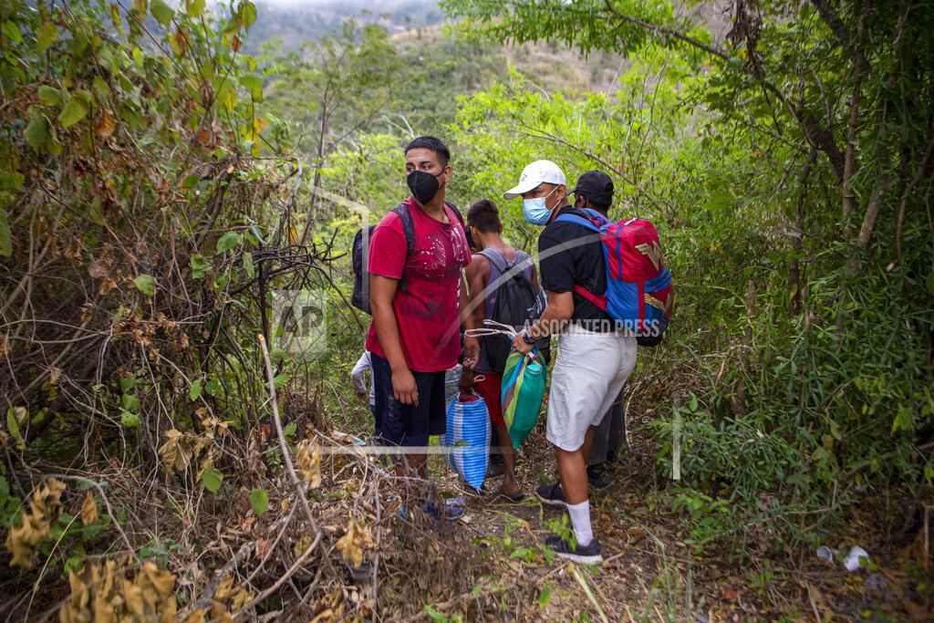 Oliver De Ros Honduran migrants observe a police checkpoint as they take an alternative route to avoid being detained in Chiquimula, Guatemala, Tuesday, Jan. 19, 2021. A once large caravan of Honduran migrants that pushed its way into Guatemala last week had dissipated by Tuesday in the face of Guatemalan security forces. (AP Photo/Oliver de Ros)