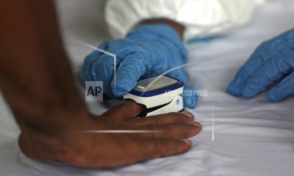 Rafiq Maqbool A health worker check the oxygen level of a resident during a free medical camp in Dharavi, one of Asia's biggest slums, in Mumbai, India, Friday, June 26, 2020. India is the fourth hardest-hit country by the pandemic in the world after the U.S., Russia and Brazil. (AP Photo/Rafiq Maqbool)