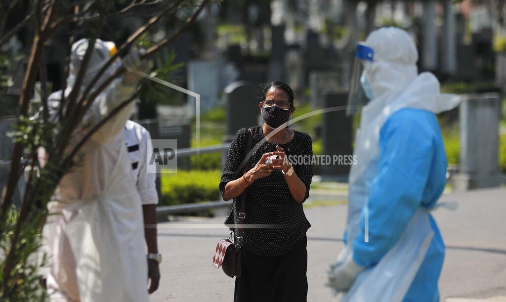 A Sri Lankan woman speaks to health workers as she attempts to attend the cremation of her family member who died of COVID-19 in Colombo, Sri Lanka, Wednesday, Feb. 10, 2021. (AP Photo/Eranga Jayawardena)