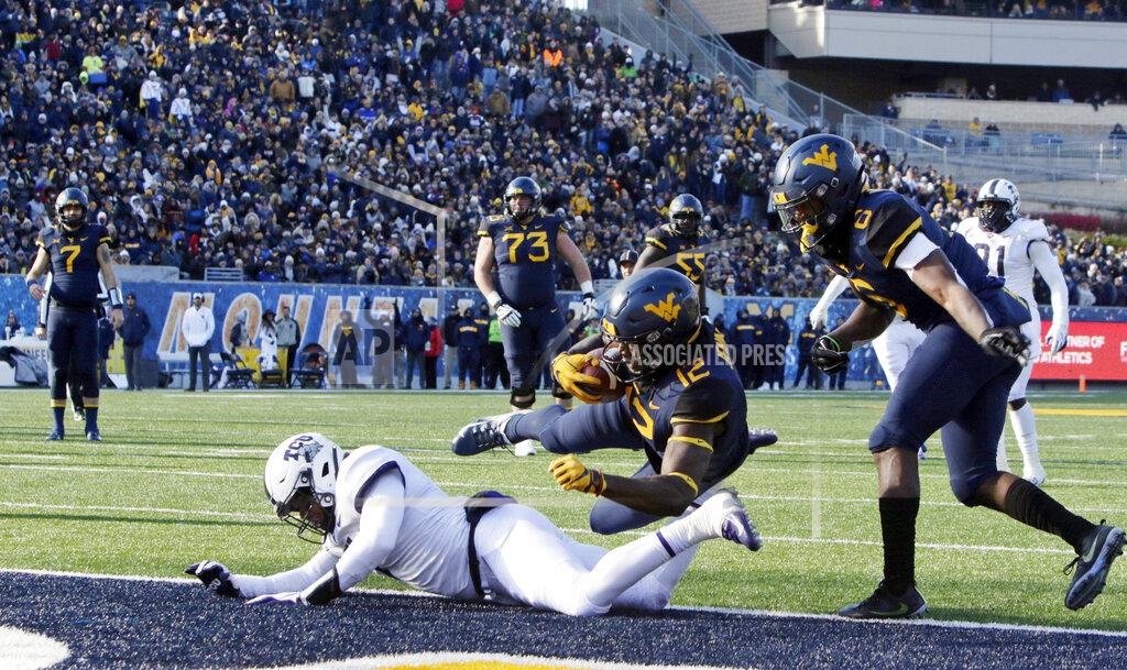 Ray Thompson FILE - In this Nov. 10, 2018, file photo, West Virginia wide receiver Gary Jennings Jr. (12) jumps over TCU linebacker Arico Evans (7) to score a touchdown during the second half of an NCAA college football game in Morgantown, W.Va. TCU and West Virginia, who meet this week, came into the Big 12 together in 2012, and have split their eight games as conference foes. TCU, coming off its first home win, is 3-0 on the road with all of those being conference games. But the Frogs lost by 37 and 24 points in their last two trips to Morgantown. (AP Photo/Raymond Thompson, File)