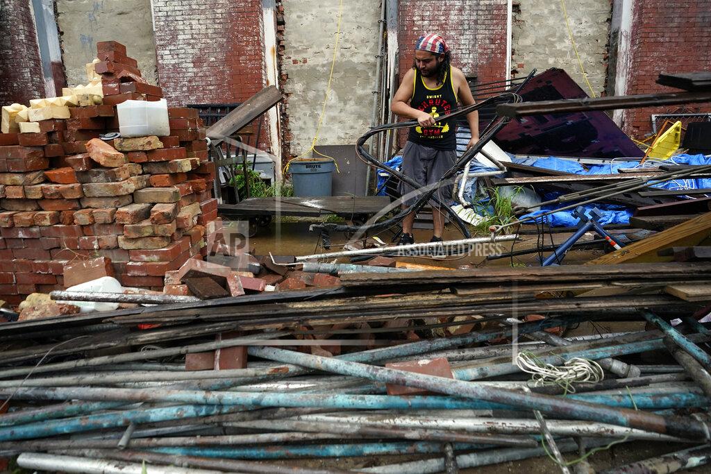David J. Phillip Adrian Bentancourt cleans up debris from a fence that was blow down by Hurricane Nicholas Tuesday, Sept. 14, 2021, in Galveston, Texas. (AP Photo/David J. Phillip)