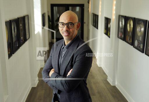 Harvey Mason jr., CEO of The Recording Academy, poses amongst commemorative records he has worked on during his career, at Harvey Mason Media music production studios, Monday, Oct. 11, 2021, in Burbank, Calif. (AP Photo/Chris Pizzello)