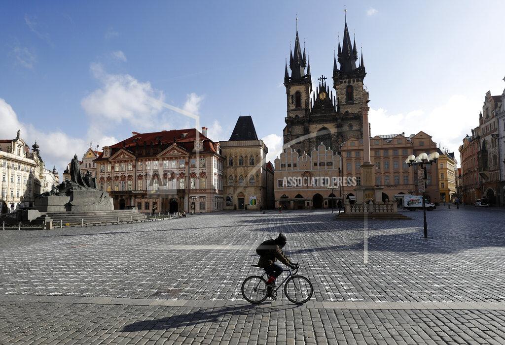 Petr David Josek A man rides his bicycle walks at the Old Town Square in Prague, Czech Republic, Monday, March 22, 2021. A group of activists painted the crosses to criticize the government's response to the coronavirus pandemic. (AP Photo/Petr David Josek)