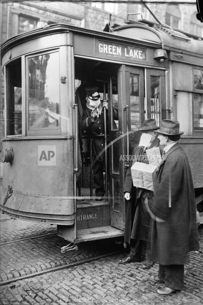Library Of Congress; The Crowley Company FILE - In this 1918-1919 photo made available by the Library of Congress, a conductor checks to see if potential passengers are wearing masks in Seattle, Wash. During the influenza epidemic, masks were required for all passengers. (Library of Congress via AP, File)