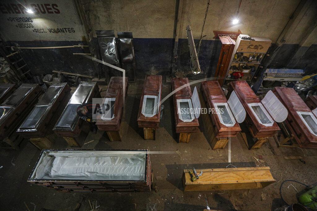 Esteban Felix Peruvian migrant coffin maker Cesar Ambrosio finishes the details on a production line of coffins at the Bergut Funeral Services in Santiago, Chile, Thursday, June 18, 2020. The coffin production has had to increase up to 120%, according to Nicolas Bergerie, owner of the factory. His more basic coffin model is called the COVID model and is made to cope with the increase of deaths during the coronavirus pandemic. (AP Photo/Esteban Felix)