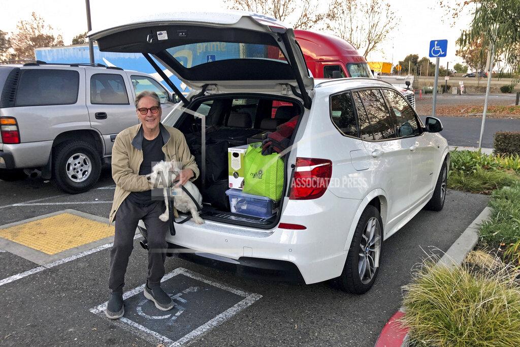 Adam Beam Matt Frinzi, 68, poses with his dog, Whitey, with his car filled with his belongings, in West Sacramento, California, on Tuesday, Dec. 15, 2020. Prinzi has lived in California for 25 years. But Tuesday he officially moved to Reno, Nevada. He said his quality of life has deteriorated so much in California that he wanted to leave. California saw its slowest growth rate on record for the nation's most populous state, adding just 21,200 people during the year that ended in July, state officials said Wednesday, Dec. 16, 2020. (AP Photo/Adam Beam)