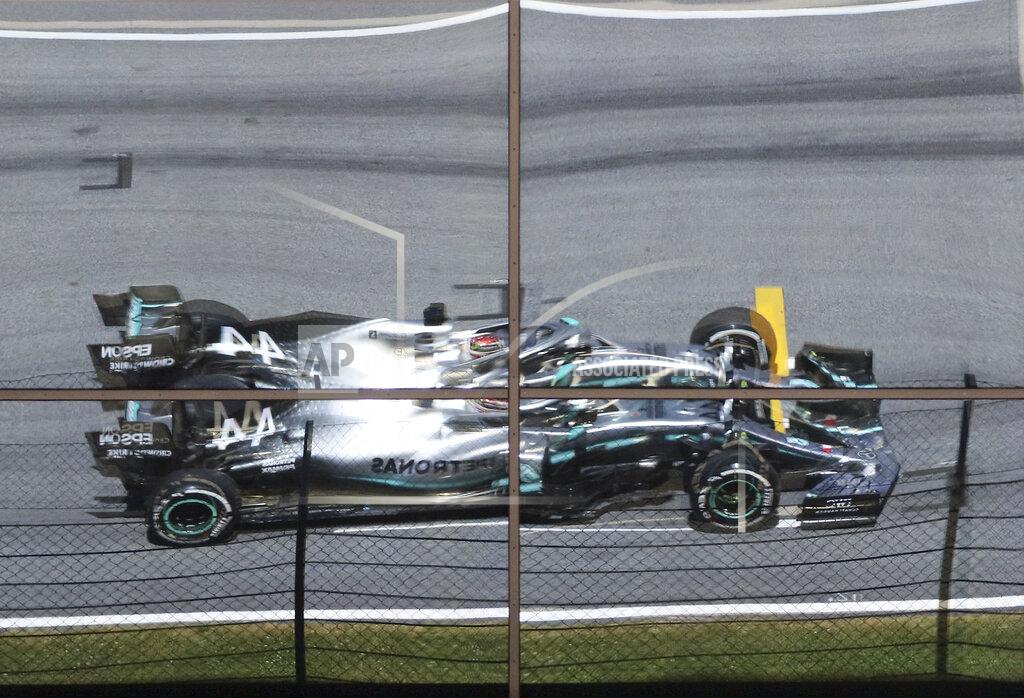 Ronald Zak Mercedes driver Lewis Hamilton of Britain is reflected on windows steering his car during the first free practice session for the Austrian Formula One Grand Prix at the Red Bull Ring racetrack in Spielberg, southern Austria, Friday, June 28, 2019. The race will be held on Sunday. (AP Photo/Ronald Zak)