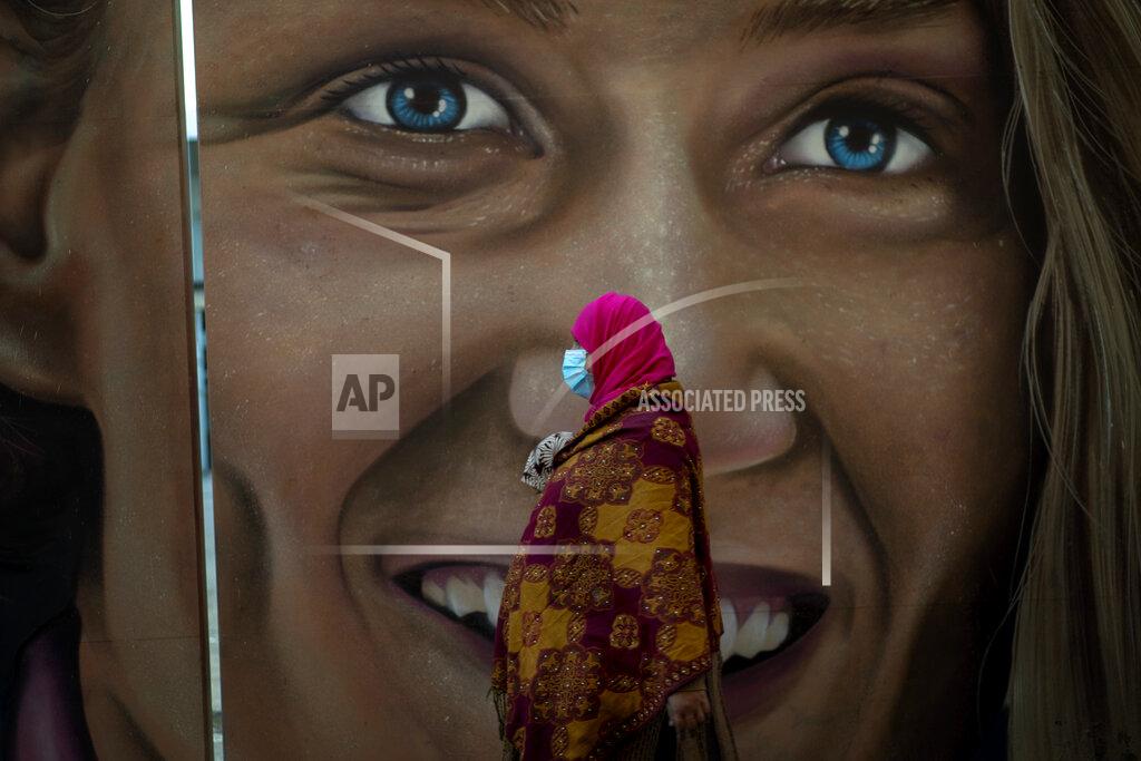 Emilio Morenatti A woman wearing a mask to prevent the spread of the coronavirus walks past a graffiti in Barcelona, Spain, Monday, Oct. 19, 2020. Several Spanish regions adopt new restrictions to deal with the health emergency. Spain is nearing one million infections since the onset of the pandemic, the most in Europe. (AP Photo/Emilio Morenatti)