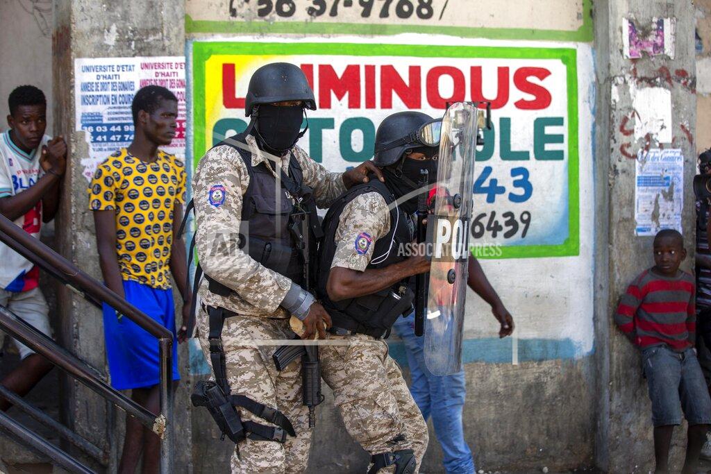 Dieu Nalio Chery Police officers take cover behind a shield as they clash with demonstrators during a protest to demand the resignation of Haitian President Jovenel Moise in Port-au-Prince, Haiti, Sunday, Feb. 7, 2021. ( AP Photo/Dieu Nalio Chery)