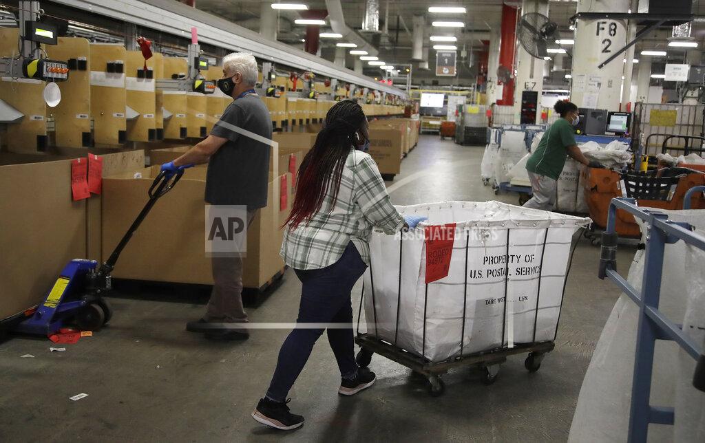 Postal workers wear masks and gloves during the coronavirus pandemic as they physically distance from each other at the United States Postal Service processing and distribution center on Thursday, April 30, 2020, in Oakland, Calif. (AP Photo/Ben Margot)
