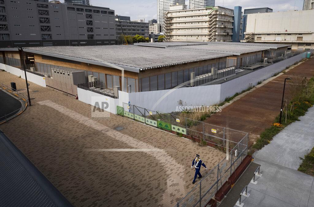 Hiro Komae A guard walks around a closed building complex being built as part of the athletes' village to be used during the postponed Tokyo 2020 Olympic and Paralympic Games, in Tokyo Thursday, April 8, 2021. Many preparations are still up in the air as organizers try to figure out how to hold the postponed games in the middle of a pandemic. (AP Photo/Hiro Komae)