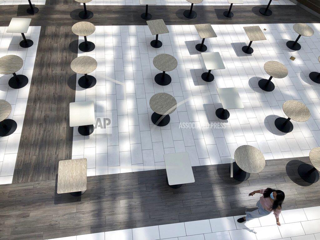 A woman wearing a protective mask walks through the mostly empty food court as Alabama's largest shopping mall, the Riverchase Galleria reopened in Hoover, Ala., Tuesday, May 5, 2020. Dozens of stores, including major retailers, remained closed as the mall opened for business for the first time during the coronavirus pandemic. (AP Photo/Jay Reeves)