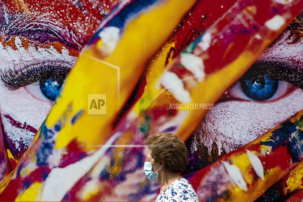 Manu Fernandez A woman wearing a face mask to prevent the spread of coronavirus walks through the Vallecas neighborhood in Madrid, Spain, Wednesday, Sept. 23, 2020. Health authorities in Madrid, Europe's hotspot in a second wave of coronavirus infections this year, might extend controversial restrictions on free movement from the hardest-hit areas of the Spanish capital to others that are emerging with increasingly higher rates of contagion. (AP Photo/Manu Fernandez)