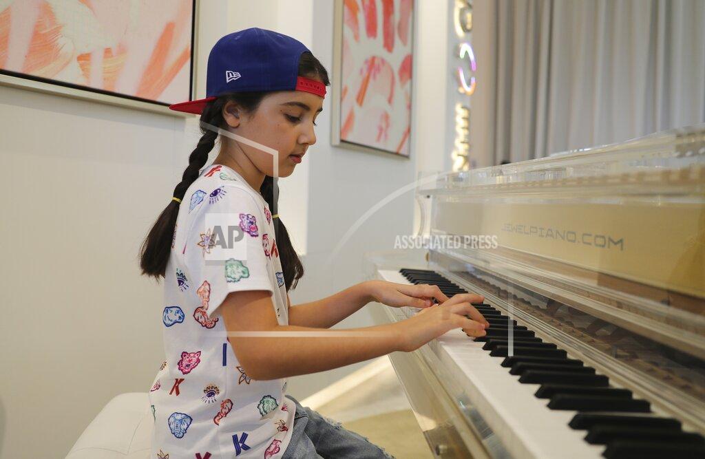 Kamran Jebreili Michelle Rasul plays piano in the lobby of her apartment building in Dubai, United Arab Emirates, Sunday, May 9, 2021. Rasul, a 9-year-old girl from Azerbaijan who lives in Dubai, is scratching her way to the top as a DJ after competing in the DMC World DJ Championship. (AP Photo/Kamran Jebreili)