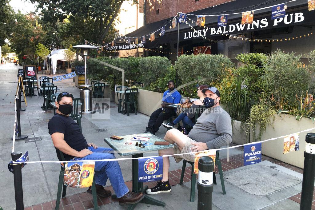 Chris Weber Anthony Angulo, left, and Jeff Koloski sit on the patio of Lucky Baldwin's pub on Monday, Nov. 30, 2020 in Pasadena, Calif. It was a rare sight after restaurants in Los Angeles County were ordered to halt serving food to diners to stop the spread of coronavirus: tables and chairs were set up outdoors in Pasadena. The city in the Los Angeles suburbs has become an island in the center of the nation's most populous county, where a surge of COVID-19 cases last week led to a three-week end to outdoor dining and California's first stay-home order since the pandemic began to spread across the state in March. (AP Photo/Christopher Weber)