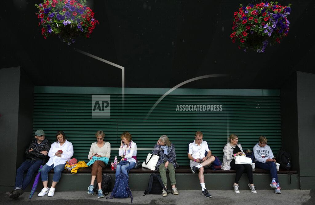 Spectators take shelter outside Court no. 2 during a rain delay on day one of the Wimbledon Tennis Championships in London, Monday June 28, 2021. (AP Photo/Kirsty Wigglesworth)