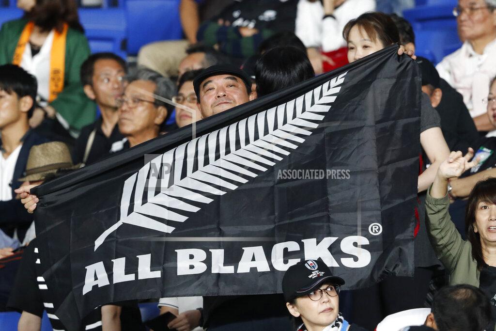 FILE - In this Sept. 21, 2019, file photo, a New Zealand fan holds an All Blacks flag and cheers for his team ahead of the start of the Rugby World Cup Pool B game between New Zealand and South Africa in Yokohama, Japan. New Zealand Rugby will make an emergency grant of $150,000 to each of its five Super Rugby teams to help them weather the next three months while the southern hemisphere tournament is suspended because of the global pandemic. (AP Photo/Shuji Kajiyama)