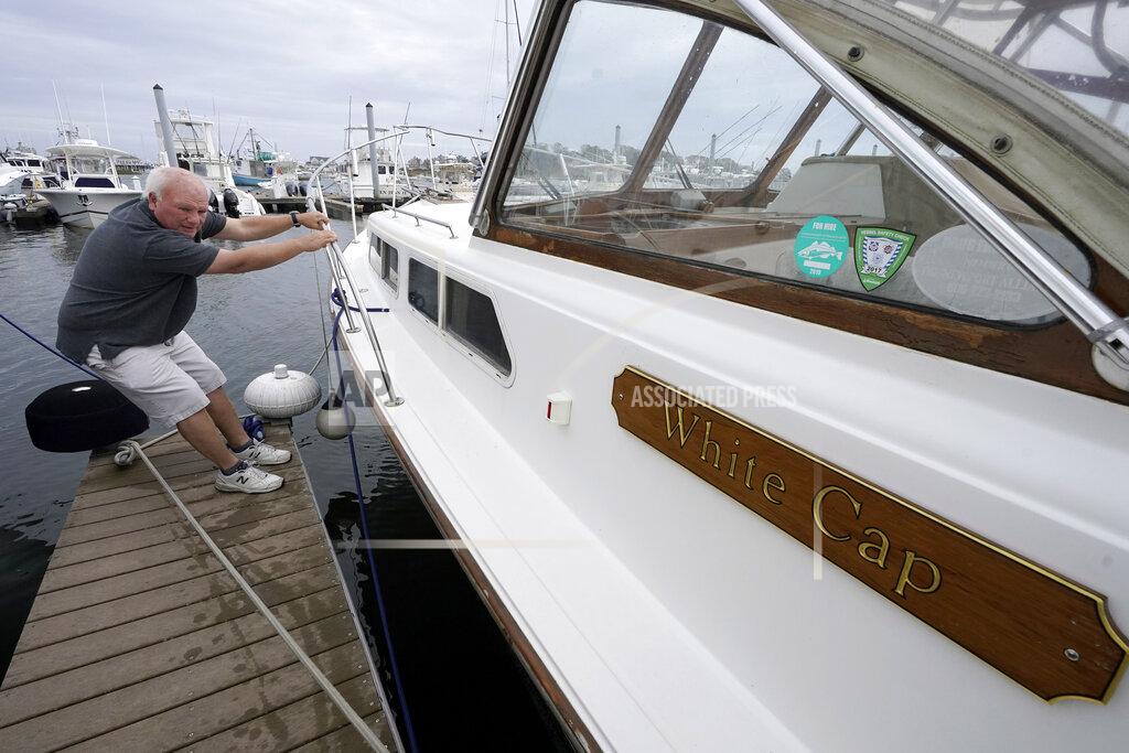 Steven Senne Brad White, of Marshfield, Mass., pulls on his 33-foot vessel White Cap to test securing lines, at Mill Wharf Marina, Tuesday, Oct. 26, 2021, in Scituate, Mass. Authorities say a powerful autumn storm is bearing down on southern New England, packing potentially damaging winds and threatening to dump as much as six inches of rain in some areas from Tuesday afternoon into Wednesday, Oct. 27. White, a licensed captain, who has been sailing out of Scituate for over 50 years, operates a service called New England Burials At Sea LLC, that provides ash scattering and full body burials at sea. (AP Photo/Steven Senne)