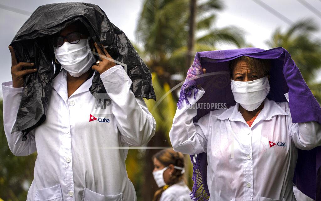 Health professionals who volunteered to travel to Kuwait to treat of coronavirus patients walk in the rain after attending their farewell ceremony in Havana, Cuba, Thursday, June 4, 2020. (AP Photo/Ramon Espinosa)