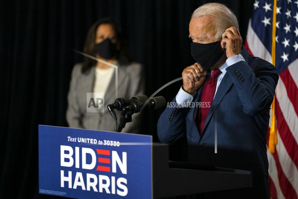 Democratic presidential candidate former Vice President Joe Biden joined by his running mate Sen. Kamala Harris, D-Calif., replaces his face mask after speaking at the Hotel DuPont in Wilmington, Del., Thursday, Aug. 13, 2020. (AP Photo/Carolyn Kaster)