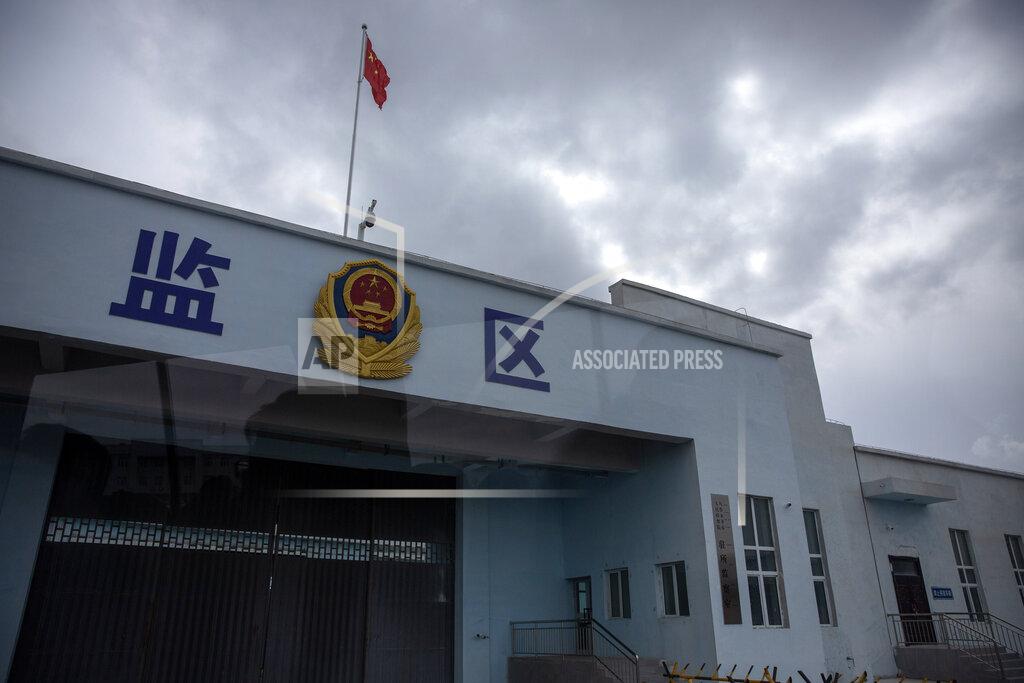 Mark Schiefelbein A Chinese national flag flies over a vehicle entrance to the inmate detention area at the Urumqi No. 3 Detention Center in Dabancheng in western China's Xinjiang Uyghur Autonomous Region, on April 23, 2021. State officials took AP journalists on a tour of a "training center" turned detention site in Dabancheng sprawling over 220 acres and estimated to hold at least 10,000 prisoners - making it by far the largest detention center in China and among the largest on the planet. Reflection in photo is from shooting through a glass window. (AP Photo/Mark Schiefelbein)