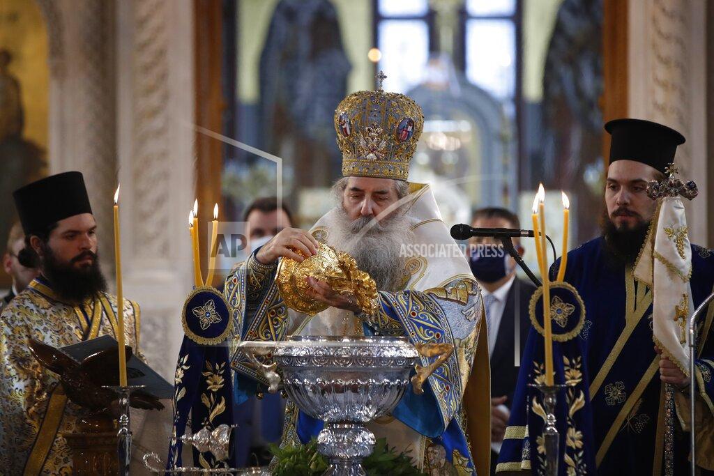 Metropolitan of Piraeus Seraphim immerses a cross into the water during the service for the feast of the Epiphany in the Church of the Holy Trinity in Piraeus, the port of Athens, Wednesday, Jan. 6, 2021. The Greek government relented and allowed limited attendance at churches celebrating the feast of the Epiphany on Wednesday, reversing a ban on attendance designed to limit the spread of the coronavirus. (AP Photo/Thanassis Stavrakis)