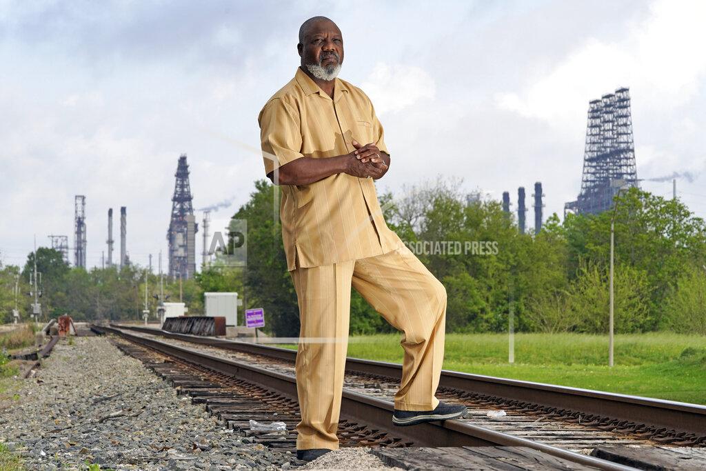 David J. Phillip Activist Hilton Kelley poses along the railroad tracks that divide East and West Port Arthur Monday, March 23, 2020, in Port Arthur, Texas. "Now we may not drop dead that day," Kelley said of the environmental protection rollbacks, and the communities surrounding the refineries and plants. "But when you're inundated day after day...we're dead. We're dead." (AP Photo/David J. Phillip)