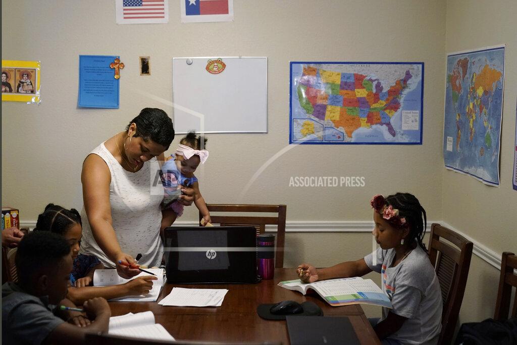 Eric Gay Arlena Brown, center, holds her youngest child, Lucy, 9 months, as she leads their other children, from left, Jacoby, 11; Felicity, 9, and Riley, 10, through math practice at their home in Austin, Texas, Tuesday, July 13, 2021. Arlena worked as a preschool teacher before the pandemic. “In the beginning, the biggest challenge was to unschool ourselves and understand that homeschooling has so much freedom,” she said. “We can go as quickly or slowly as we need to.” (AP Photo/Eric Gay)