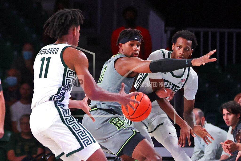 Tim Aylen In this photo provided by Bahamas Visual Services, Michigan State's Marcus Bingham Jr., right, passes the ball to guard A.J. Hoggard (11) as Baylor's Flo Thamba defends during an NCAA college basketball game at Paradise Island, Bahamas, Friday, Nov. 26, 2021. (Tim Aylen/Bahamas Visual Services via AP)