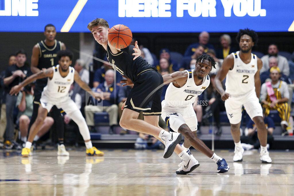 Kathleen Batten Oakland guard Blake Lampman (11) reaches for the ball as West Virginia guard Kedrian Johnson (0) defends during the second half of an NCAA college basketball game in Morgantown, W.Va., Tuesday, Nov. 9, 2021. (AP Photo/Kathleen Batten)