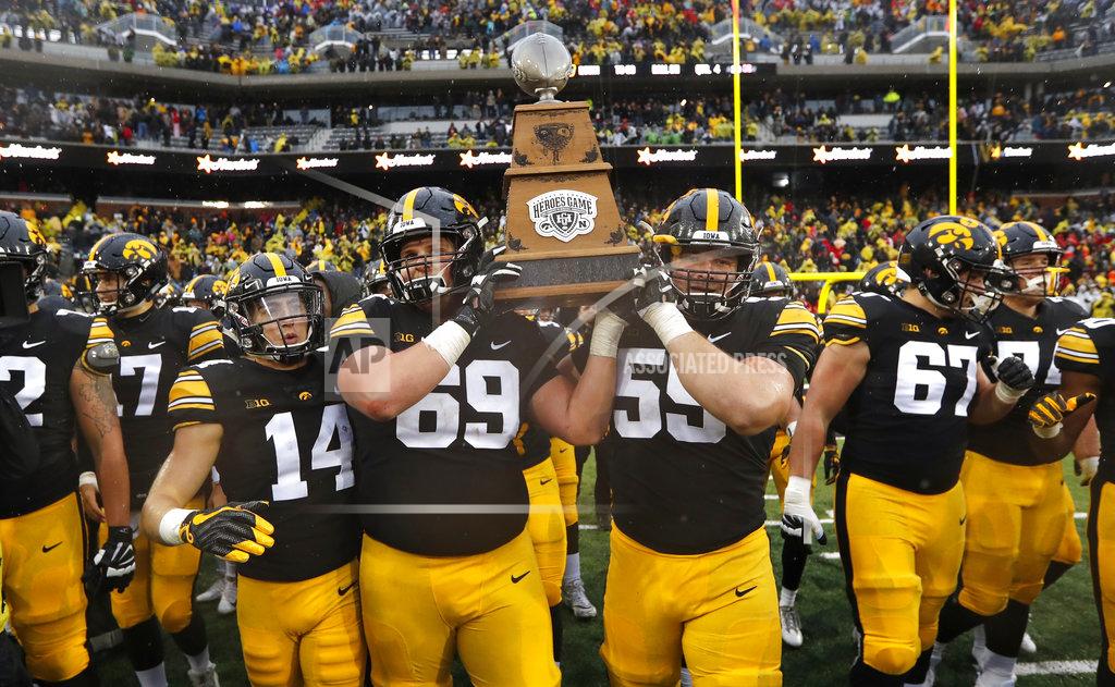 Charlie Neibergall Iowa's Kyle Groeneweg (14), Keegan Render (69) and Ross Reynolds (59) carry the Heroes Trophy off the field after defeating Nebraska 31-28 in an NCAA college football game, Friday, Nov. 23, 2018, in Iowa City, Iowa. (AP Photo/Charlie Neibergall)