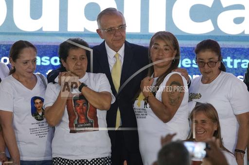 Colombia's Defense Minister Ivan Velasquez, center, stands with the relatives of 19 young people who were falsely presented as guerrillas killed in combat by the Colombian army during the country's internal conflict, during an act of recognition and public apology by the state for their extrajudicial execution, in Bogota, Colombia, Tuesday, Oct. 3, 2023. (AP Photo/Fernando Vergara)