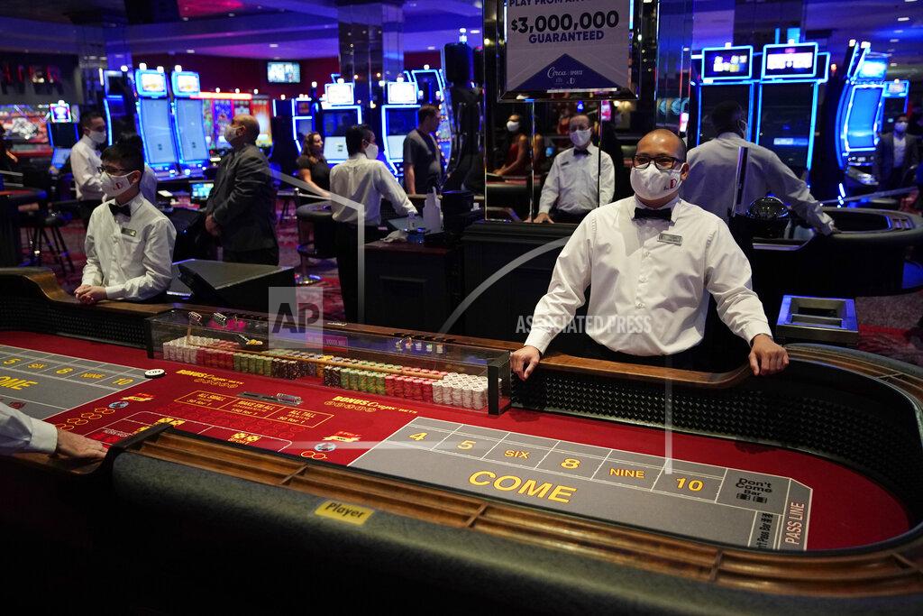 John Locher FILE - Dealers in masks wait for customers before the reopening of the D Las Vegas hotel and casino in Las Vegas, in this Wednesday, June 3, 2020, file photo. Governments and businesses are scrambling to change course following new federal guidance calling for the return of mask wearing in virus hot spots amid a dramatic spike in COVID-19 cases and hospitalizations nationwide. Nevada and Kansas City were among the locations that moved swiftly to re-impose indoor mask mandates following Tuesday’s announcement from the Centers for Disease Control and Prevention. (AP Photo/John Locher, FIle)