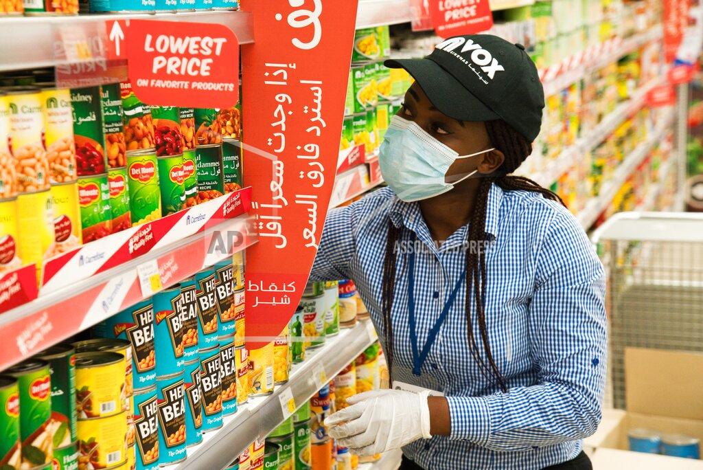 Jon Gambrell In this April 19, 2020 photo, Vox Cinema employee Jackline Nansamba of Uganda stocks shelves at a Carrefour supermarket while wearing a face mask amid the coronavirus pandemic in Dubai, United Arab Emirates. The coronavirus pandemic has exposed just how vital foreigners are to the Gulf Arab countries where they work as medics, drivers, grocers and cleaners. Vox Cinemas and Carrefour are both owned in the United Arab Emirates by the major retail firm Majid Al Futtaim. (AP Photo/Jon Gambrell)