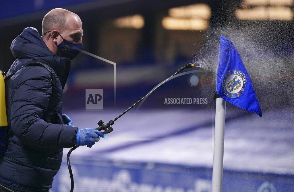 John Walton A groundsman sprays disinfectant on a corner flag during a break in the English Premier League soccer match between Chelsea and West Ham at Stamford Bridge, London, Monday, Dec. 21, 2020. (AP Photo/John Walton,Pool)
