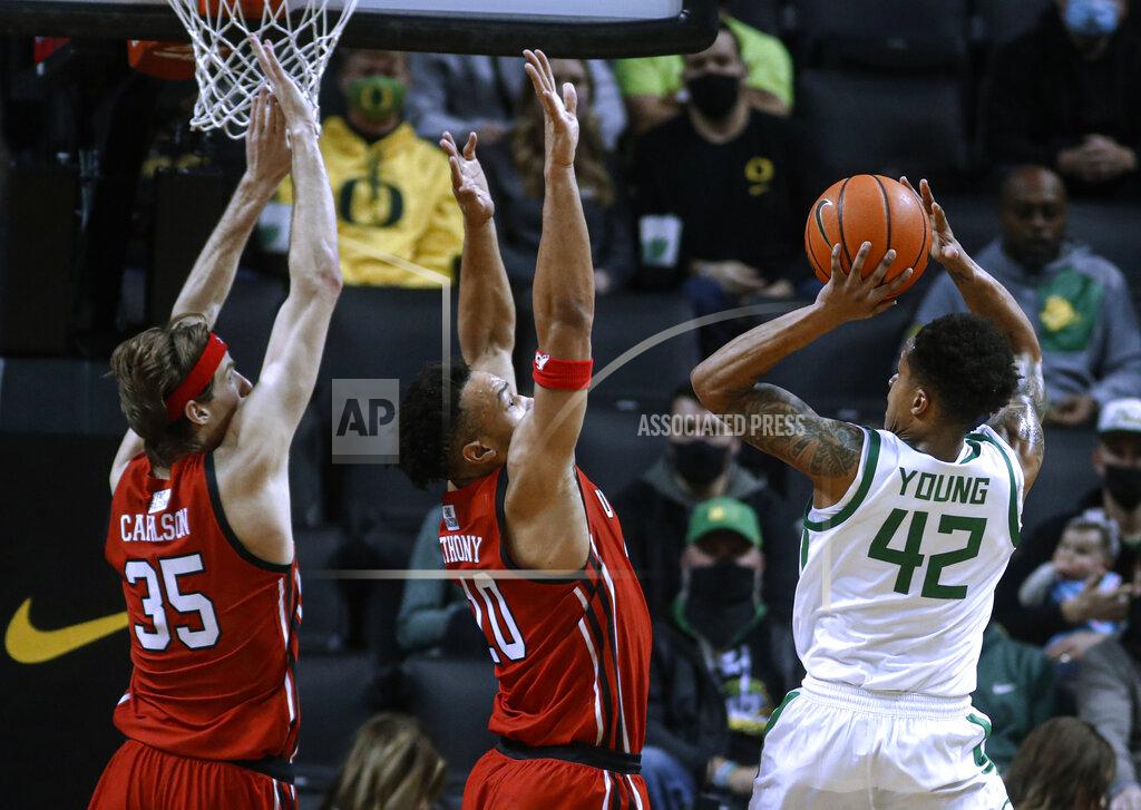 Thomas Boyd Oregon guard Jacob Young (42) shoots as Utah's Brendan Carlson, left, and Marco Anthony defend during the second half of an NCAA college basketball game in Eugene, Ore., Saturday, Jan. 1, 2022. (AP Photo/Thomas Boyd)