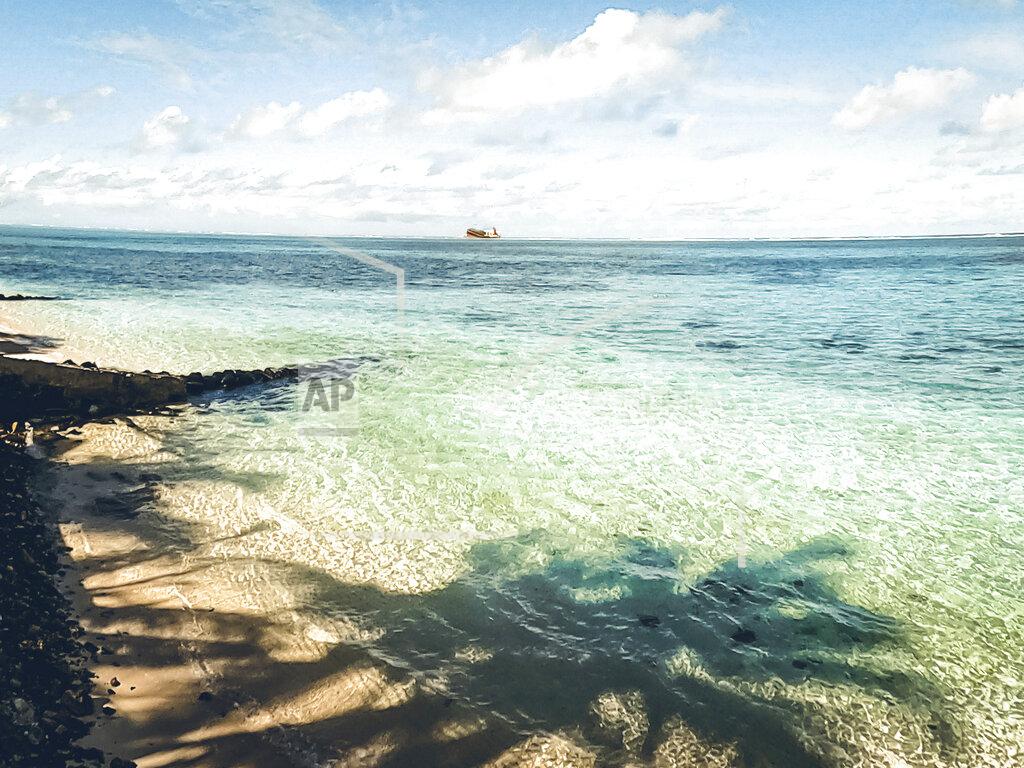 Uncredited In this photo provided by Grégoire Rouxel is a ship in the distance that ran aground in the ocean earlier this week, Friday, Aug. 7, 2020, in Mauritius. The Indian Ocean island of Mauritius has declared a "state of environmental emergency" after a Japanese-owned ship that ran aground offshore days ago began spilling tons of fuel. Prime Minister Pravind Jugnauth announced the development late Friday, Aug. 7, as satellite images showed a dark slick spreading near environmental areas the government called "very sensitive." (@gregrouxel via AP)