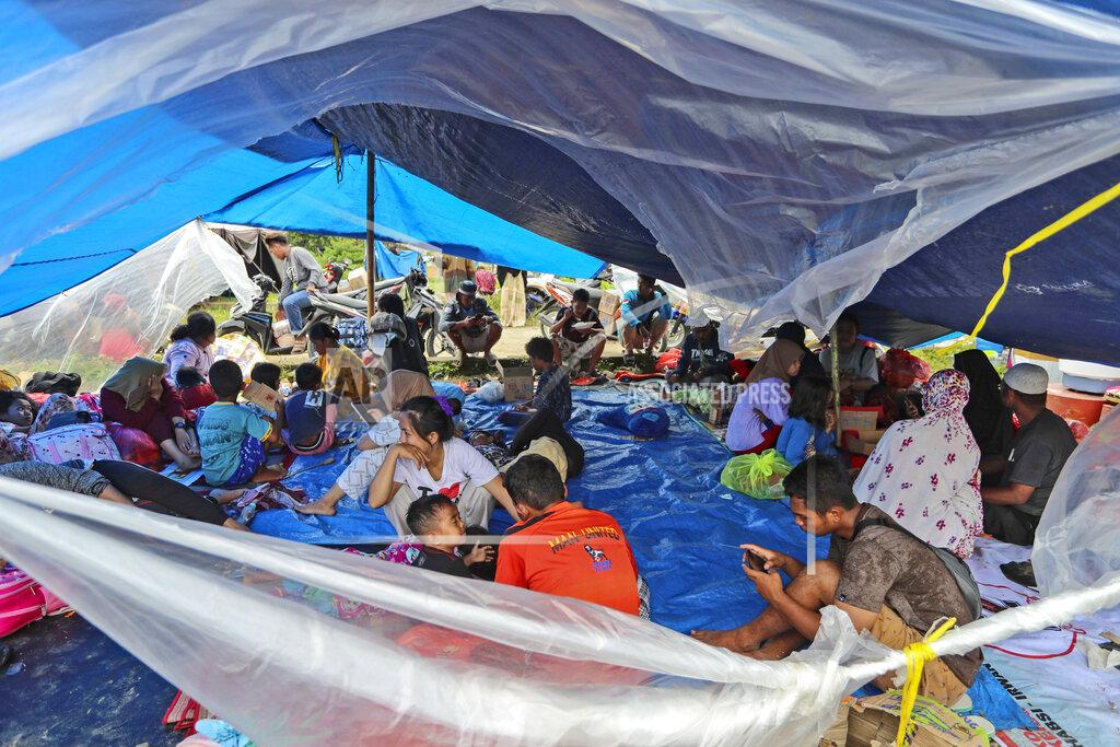 Joshua Marunduh People who are displaced by an earthquake sit under in a makeshift tent at a temporary shelter in Mamuju, West Sulawesi, Indonesia, Sunday, Jan. 17, 2021. Rescuers retrieved more bodies from the rubble of homes and buildings toppled by the magnitude 6.2 earthquake while military engineers managed to reopen ruptured roads to clear access for relief goods. (AP Photo/Joshua Marunduh)