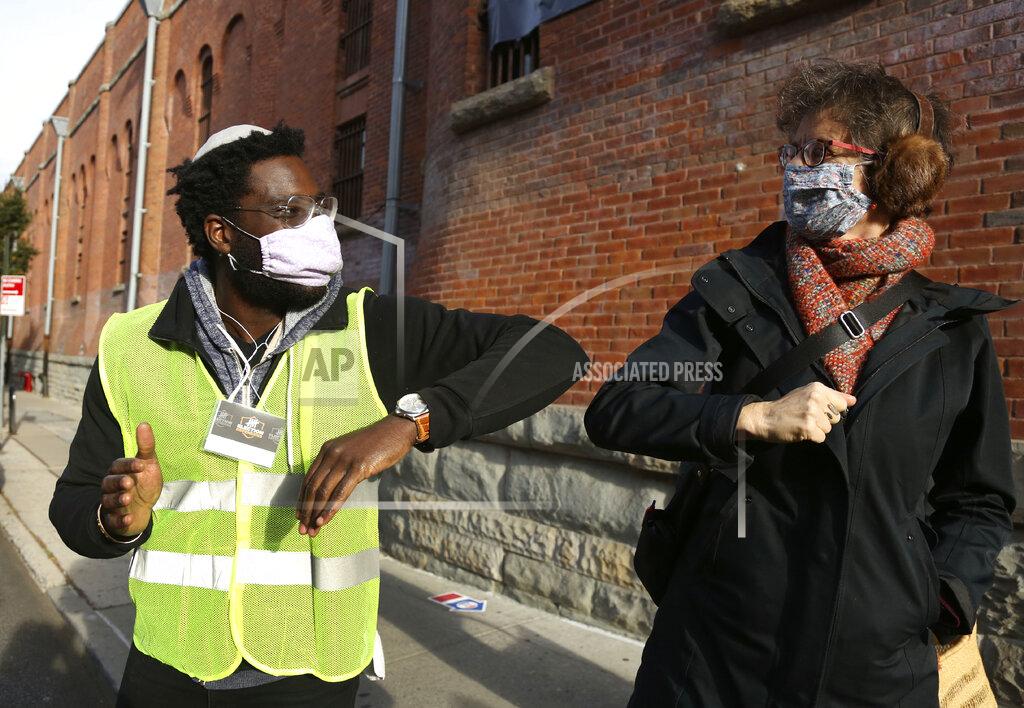 Yehudah Webster with the Frontline Poll Defenders group, left, greets Jewish Cantor Lisa B. Segal after she and a friend voted on Election Day at the Park Slope Armory YMCA in the Brooklyn borough of New York, Tuesday, Nov. 3, 2020. Webster says it's important that faith leaders like himself are there to create "supportive and safe conditions for voters" as they have prepared to help de-escalate disruptive or intimidating tactics at the polls. (AP Photo/Jessie Wardarski)