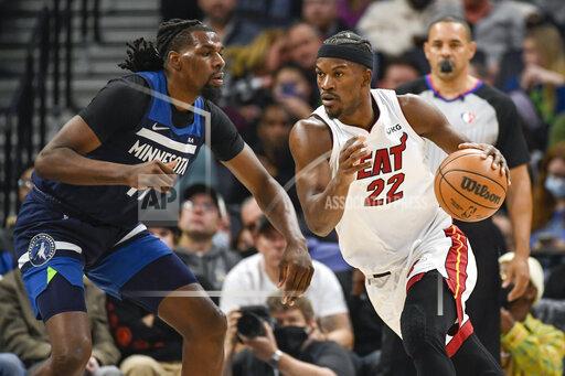Miami Heat forward Jimmy Butler (22) drives past Minnesota Timberwolves center Naz Reid during the first half of an NBA basketball game Wednesday, Nov. 24, 2021, in Minneapolis. (AP Photo/Craig Lassig)