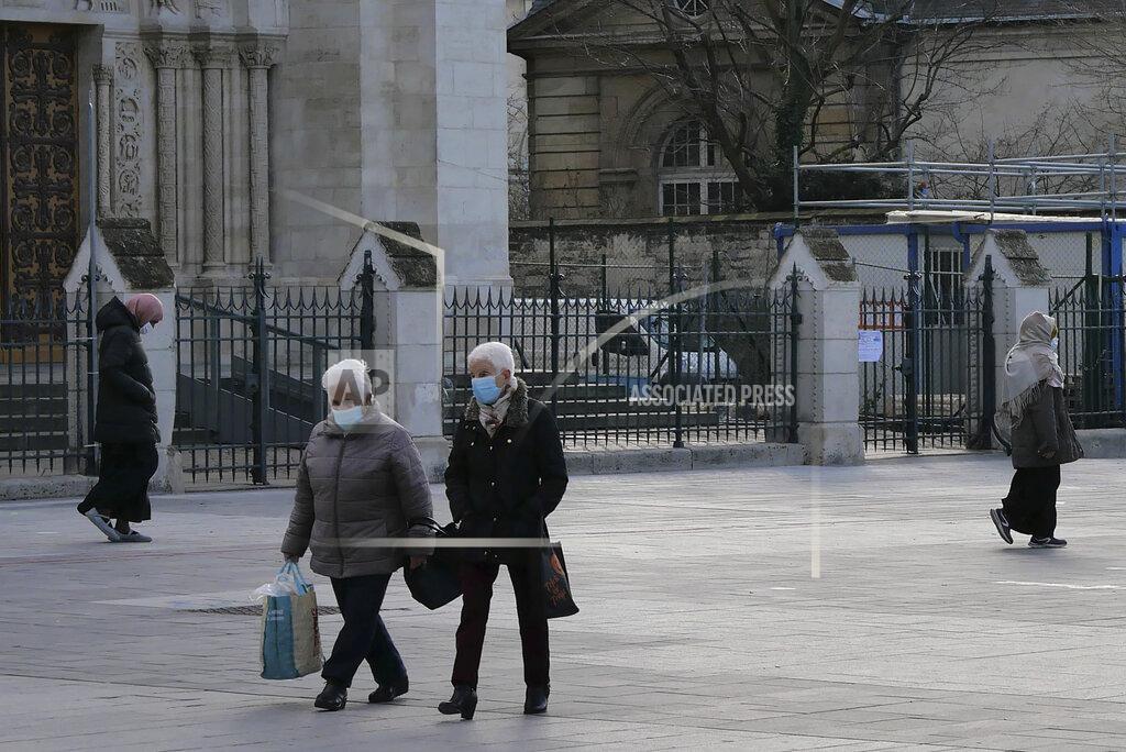 Christophe Ena People walk past the Saint-Denis basilica, outside Paris, Monday, Jan. 25, 2021. Many people lining up for vaccines in the Paris suburb are particularly grateful for the injections. The surrounding region is the poorest in mainland France, with 130 languages spoken and the country's highest rise in mortality last spring. (AP Photo/Christophe Ena)