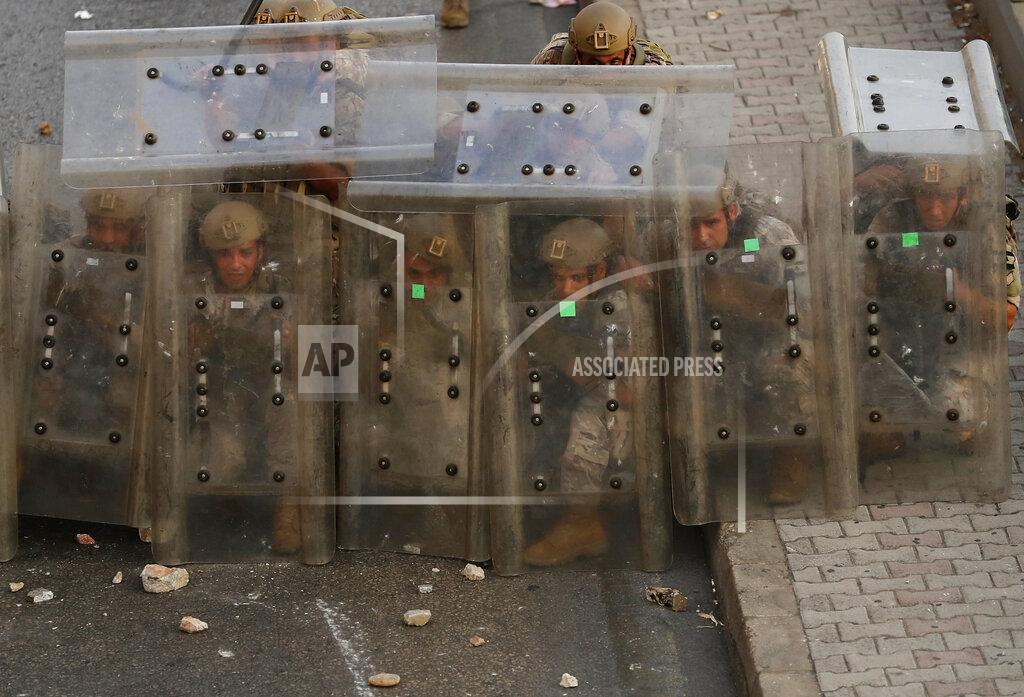 Hussein Malla Lebanese soldiers hide from stones behind their protective shields as they clash with supporters of Prime Minister-designate Saad Hariri who stepped down on Thursday in Beirut, Lebanon, Thursday, July 15, 2021. Hariri cited citing "key differences" with the country's president, Michel Aoun, when he made the announcement, nine months after he was named to the post by the parliament. (AP Photo/Hussein Malla)