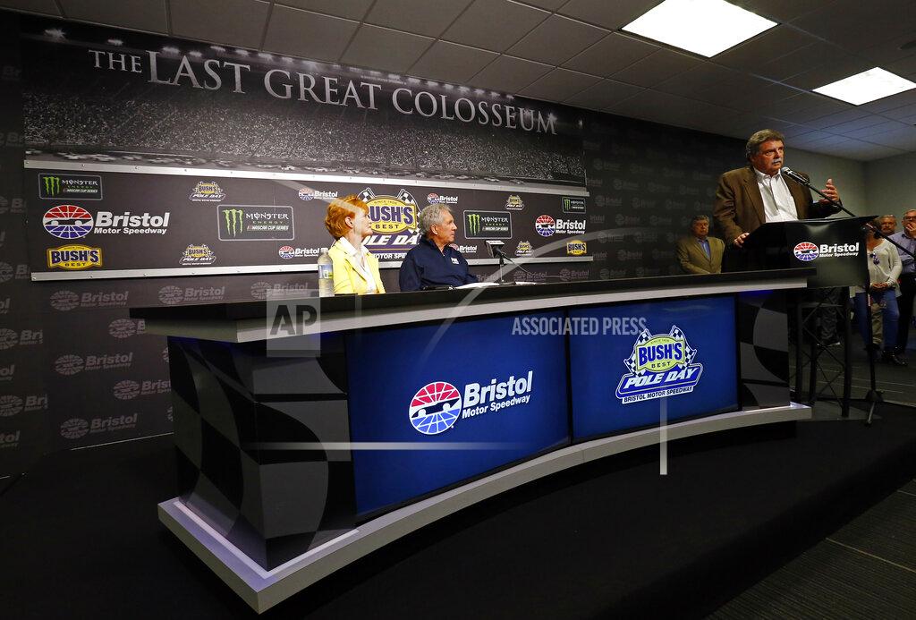 Wade Payne THIS CORRECTS THAT MIKE HELTON IS VICE-CHAIRMAN, NOT VICE-PRESIDENT - Hall of Fame driver and FOX television announcer Darrell Waltrip, center, and his wife, Stevie, listen as Mike Helton, NASCAR vice-chairman, speaks to media during a press conference announcing Waltrip's retirement from the booth before practice for a NASCAR Cup Series auto race, Friday, April 5, 2019, in Bristol, Tenn. (AP Photo/Wade Payne)