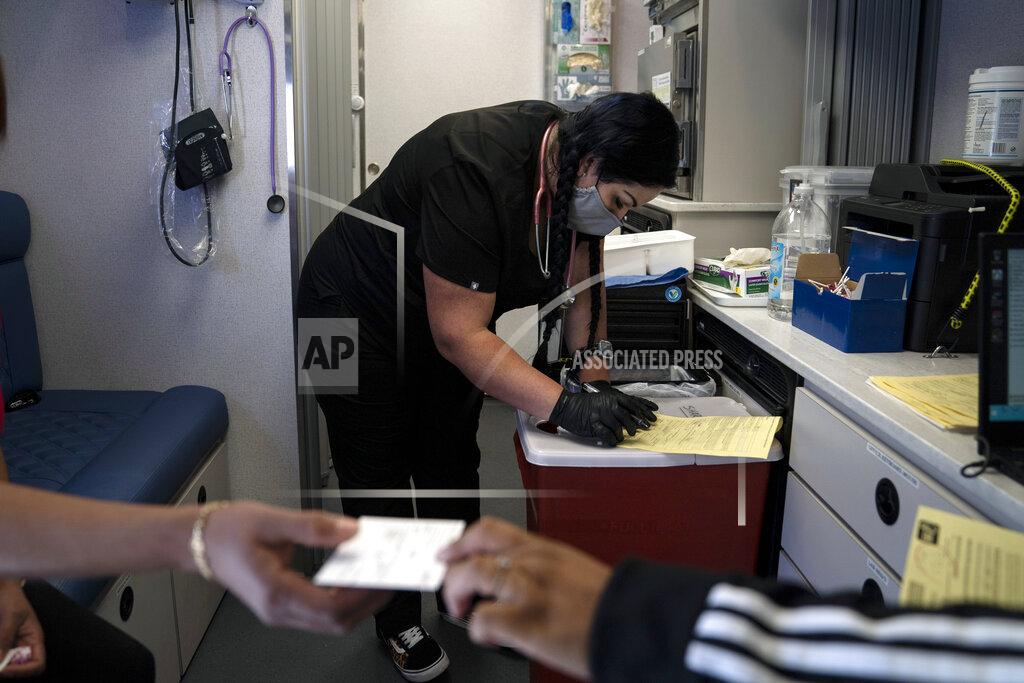 Jae C. Hong Nurse Natasha Garcia does paperwork after administering a dose of the Moderna COVID-19 vaccine to Magaly Esparza, foreground left, at a mobile clinic set up in the parking lot of a shopping center in Orange, Calif., Thursday, April 29, 2021. The mobile unit, launched in February by Families Together of Orange County, began its service to provide better access to the COVID-19 vaccine within the community and to prevent vaccine hesitation, according to mobile operations manager Parsia Jahanbani. "There's a lot of people that are hesitant to go to vaccine centers to get vaccinated for various reasons. They might be afraid of not having paperwork. They might be afraid of not being able to take time off from work," said Jahanbani. (AP Photo/Jae C. Hong)